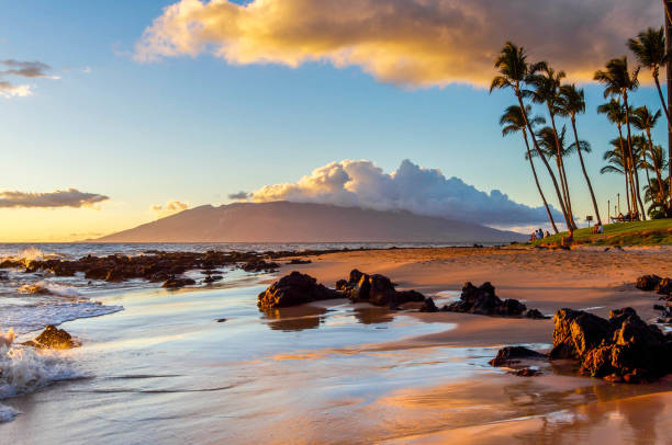 The glow of sunset is reflected on a Maui beach.